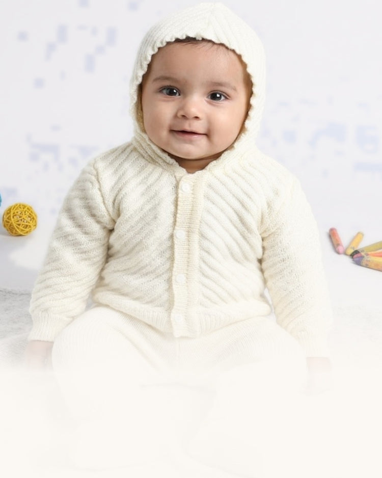 Baby in a cream hooded knit set by Little Angels